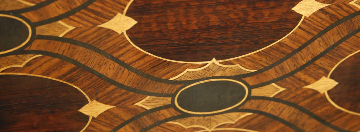  这是一架 Bluthner 博兰斯勒三角钢琴，外壳为蓝花楹，镶嵌有精美的图案。琴腿处有华丽的雕刻和青铜的配饰。